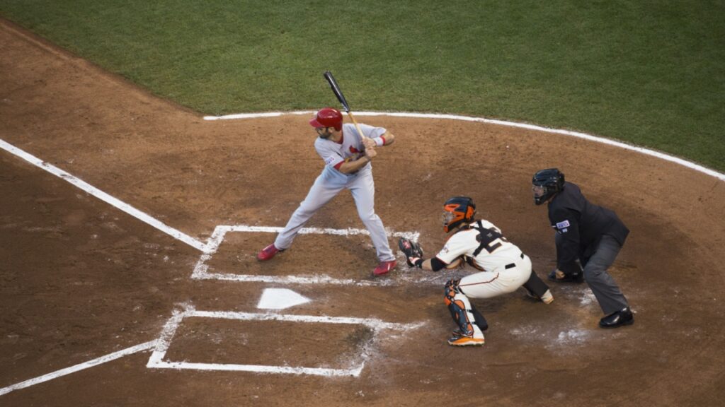 A batter preparing to play a pitch in a stadium with the catcher and umpire behind.
