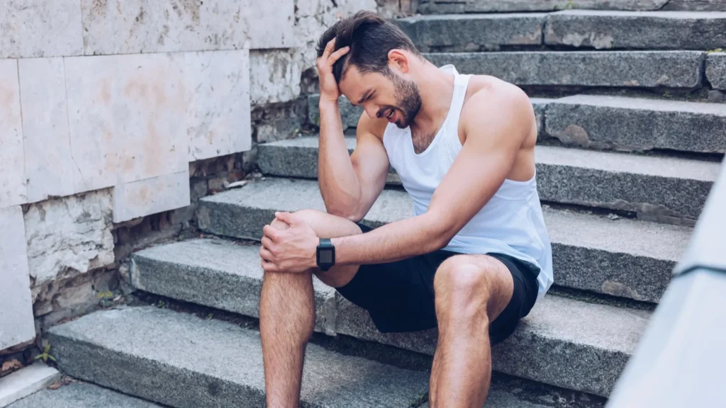 injured sportsman suffering from pain while sitting on stairs and - Gameday Chatter Injured sportsman suffering from pain while sitting on stairs.