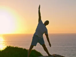 Muscular athlete silhouette stretching at sea.