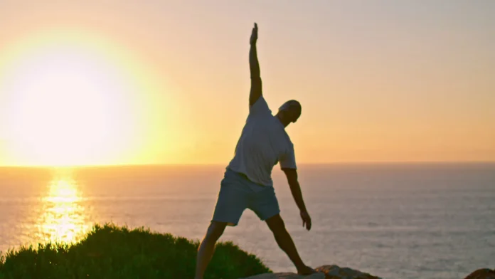 Muscular athlete silhouette stretching at sea.