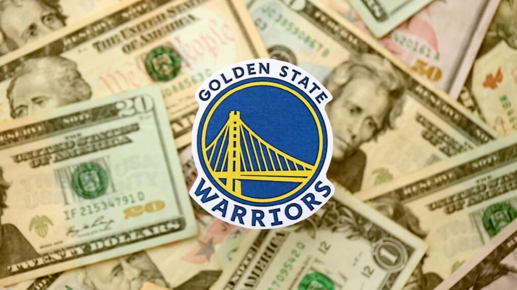 Shutterstock_Golden State Warriors_ 2621936935 - Gameday Chatter Golden State Warriors basketball team badge lies on big amount of US dollar bills.