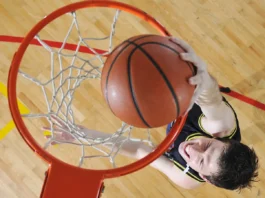 A basketball player, viewed from above, dunks a basketball into a hoop.