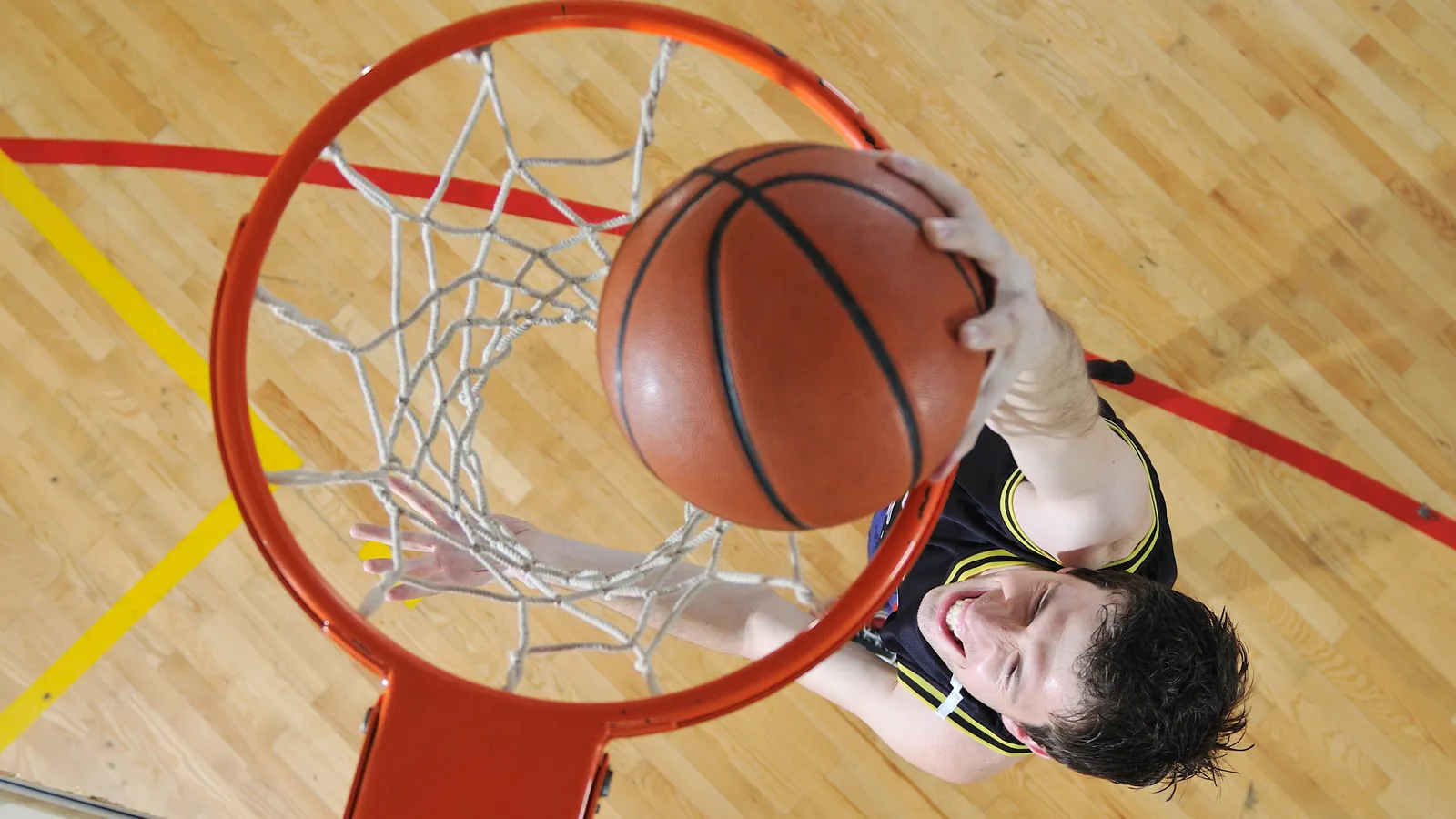 A basketball player, viewed from above, dunks a basketball into a hoop.