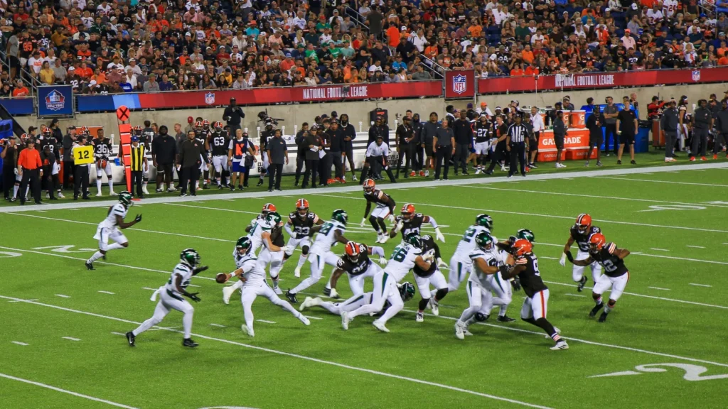 NFL offensive line blocking defenders during running play in the stadium.