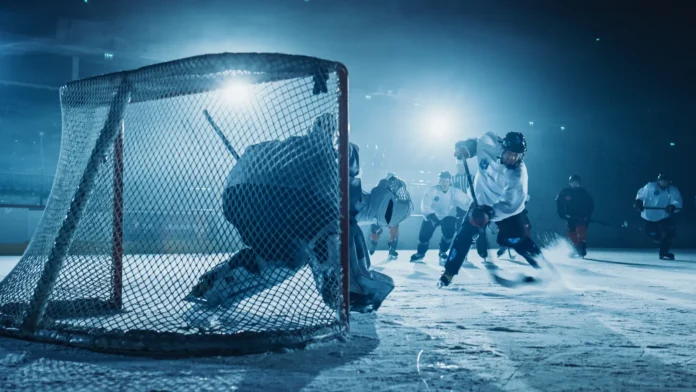 An ice hockey rink arena with a goalie against forward player.