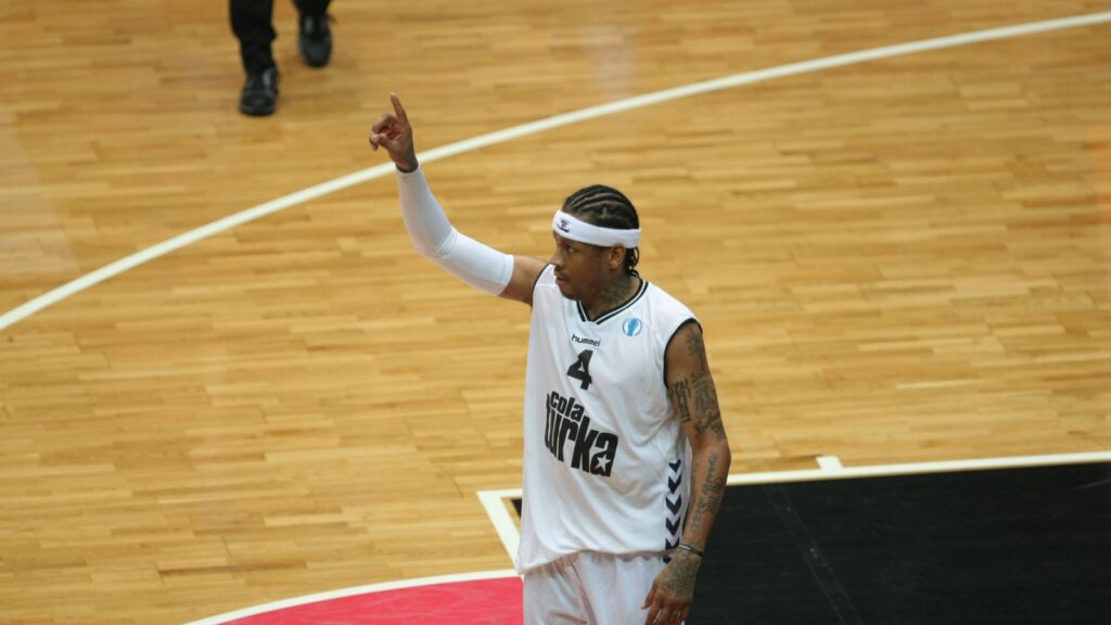 Allen Iverson raising one hand on a basketball court.