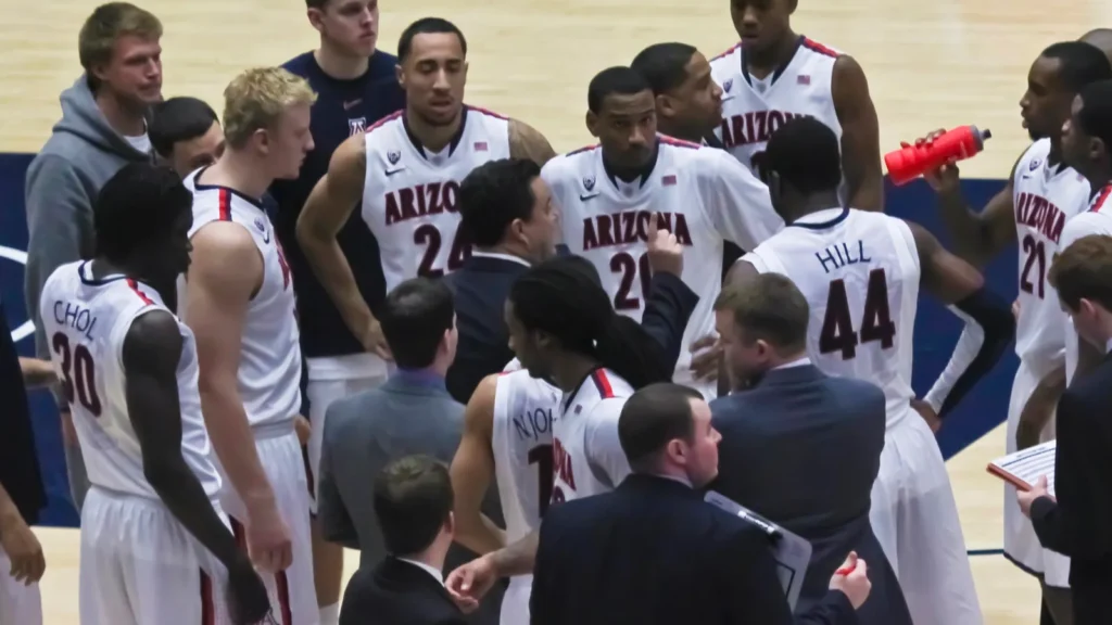 Basketball team huddles around coaches during a timeout.