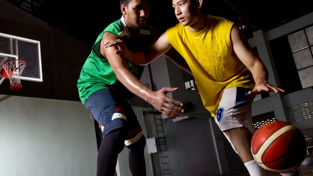 Two basketball players competing for the ball on an indoor court.