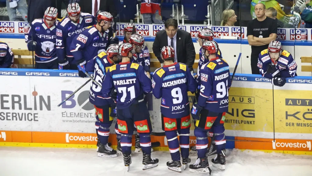 The hockey team gathered around the coach, receiving strategic guidance during a game break.