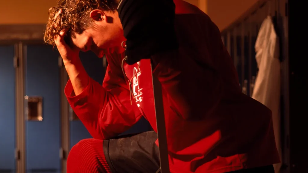 A hockey player in the dressing room looking dejected.