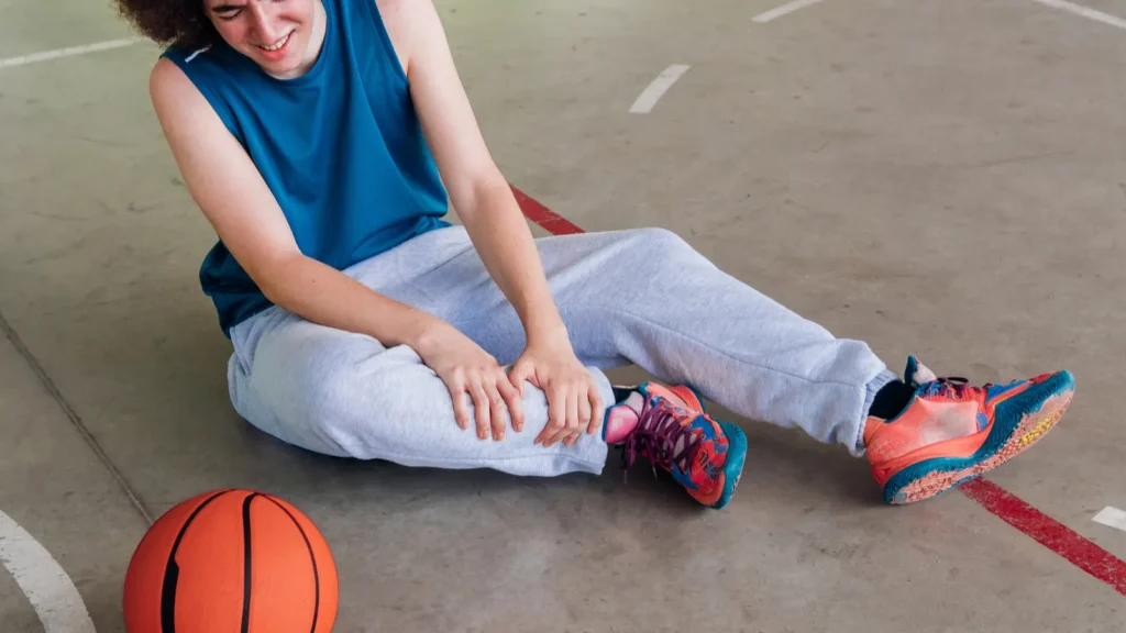 An injured basketball player sitting on the floor.