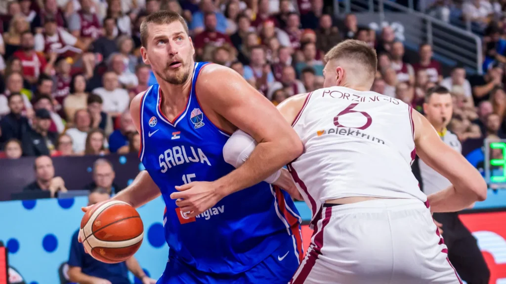 Nikola Jokic dribbles for Serbia while being defended during an international basketball game.