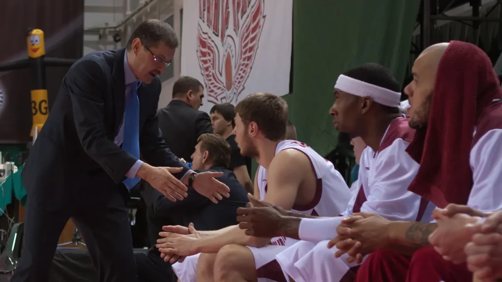 Coach gestures to the seated basketball players on the bench.