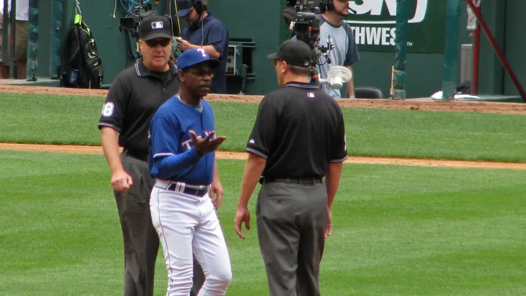 Baseball player discussing a call with umpires on the field during a game.