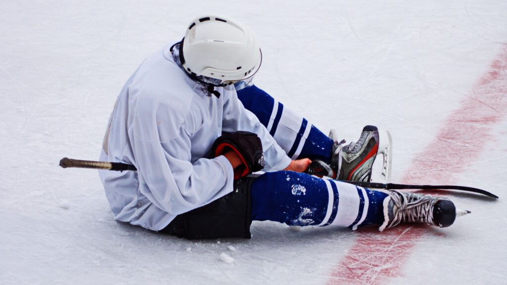 Hockey player sitting on the ice with disappointment.