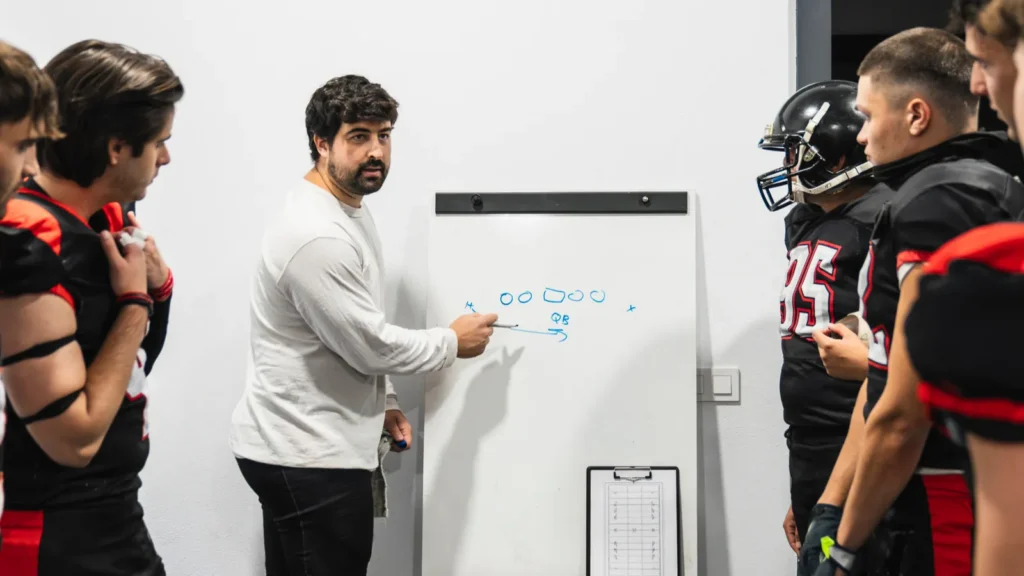 american football coach discussing game strategy on a whiteboard with