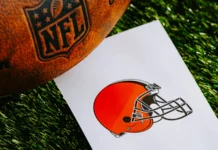 A professional American football, branded with the NFL logo, placed alongside a piece of paper displaying the logo of the Cleveland Browns team.