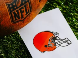 A professional American football, branded with the NFL logo, placed alongside a piece of paper displaying the logo of the Cleveland Browns team.
