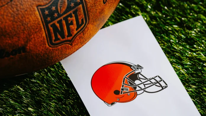 A professional American football, branded with the NFL logo, placed alongside a piece of paper displaying the logo of the Cleveland Browns team.