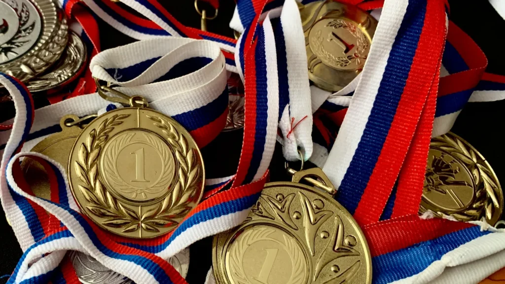 gold silver bronze medals and cups on a black background