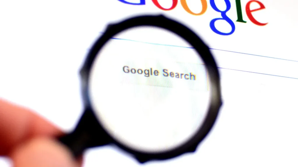 hand holds magnifying glass against google homepage