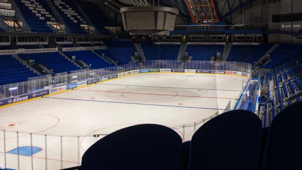 An Empty ice hockey arena with blue seats.