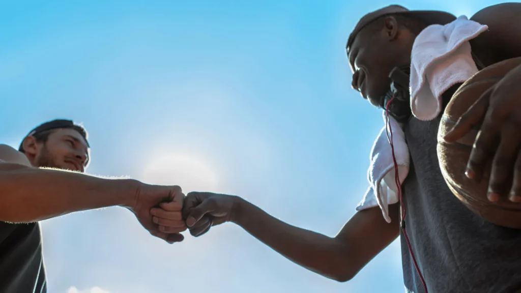 Two basketball players fist bumping against the sky.