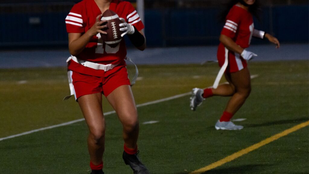A flag football player prepares to throw during a night game.