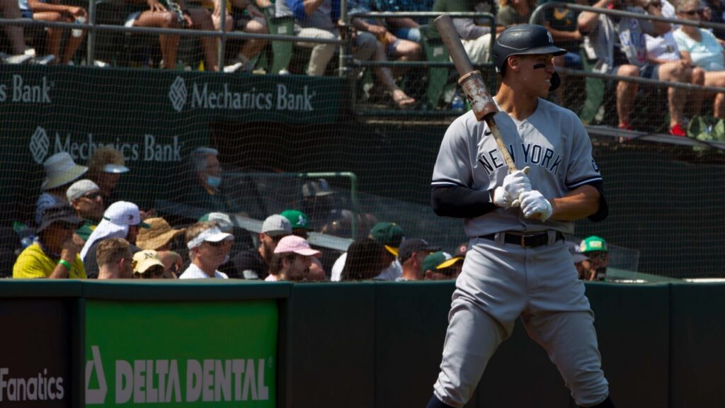 Aaron Judge standing on the field holding a bat.