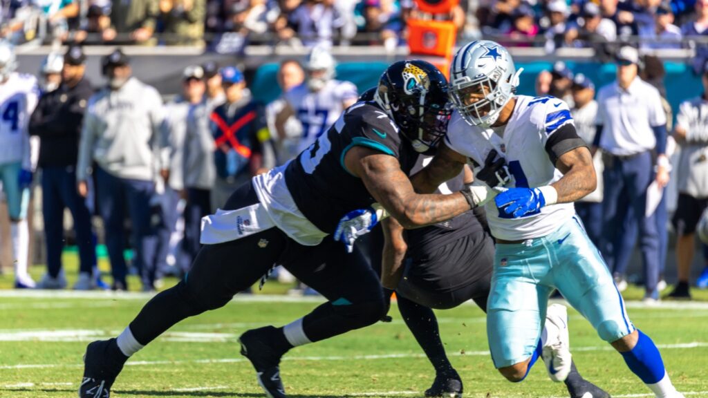 Two NFL football players, one in a black Jacksonville Jaguars uniform and Micah Parsons in Dallas Cowboys uniform, collide during a game.