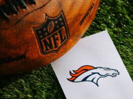 Denver Broncos NFL team logo and American football ball on green grass.