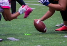 Tom Brady’s Fanatics Flag Football Classic relocates from Riyadh to Los Angeles A closeup shot of American football players kicking off a match on a green field
