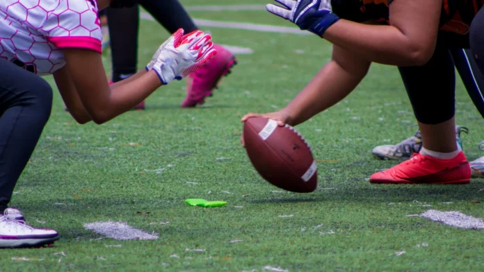 A closeup shot of American football players kicking off a match on a green field