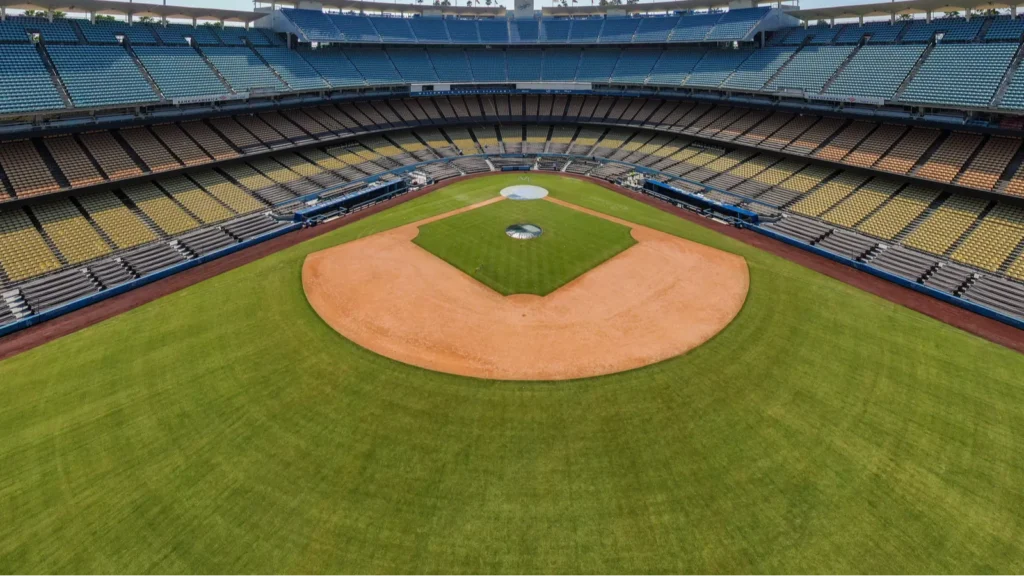 A highaltitude aerial perspective of Dodger Stadium in Los Angeles showing the iconic multicolored tiered seating the pristine grass field with the