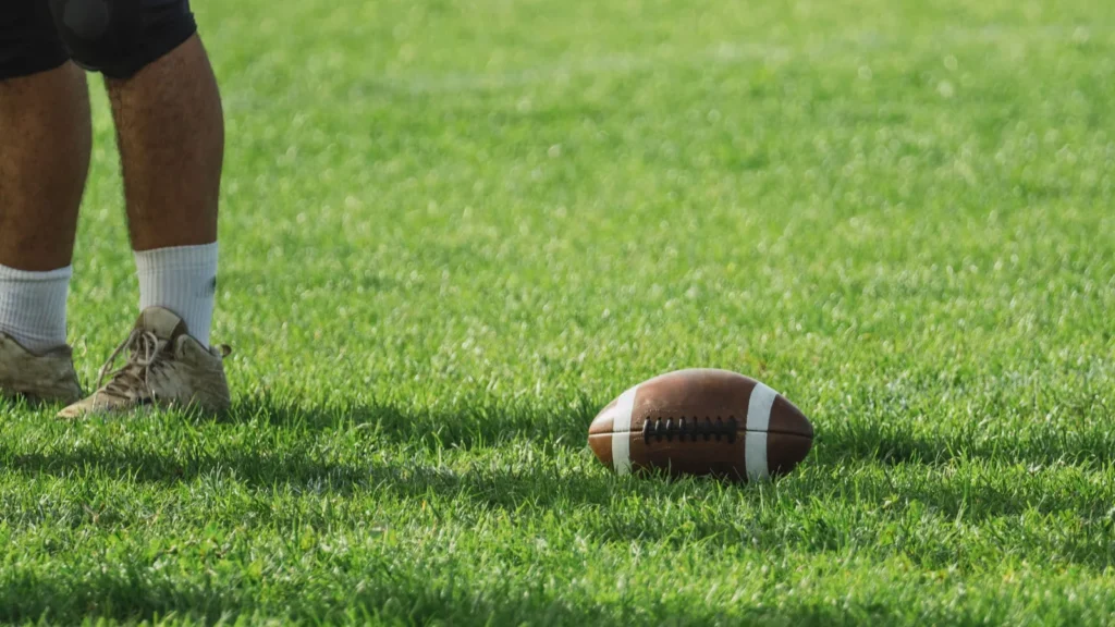 An American football player with a ball on the green field