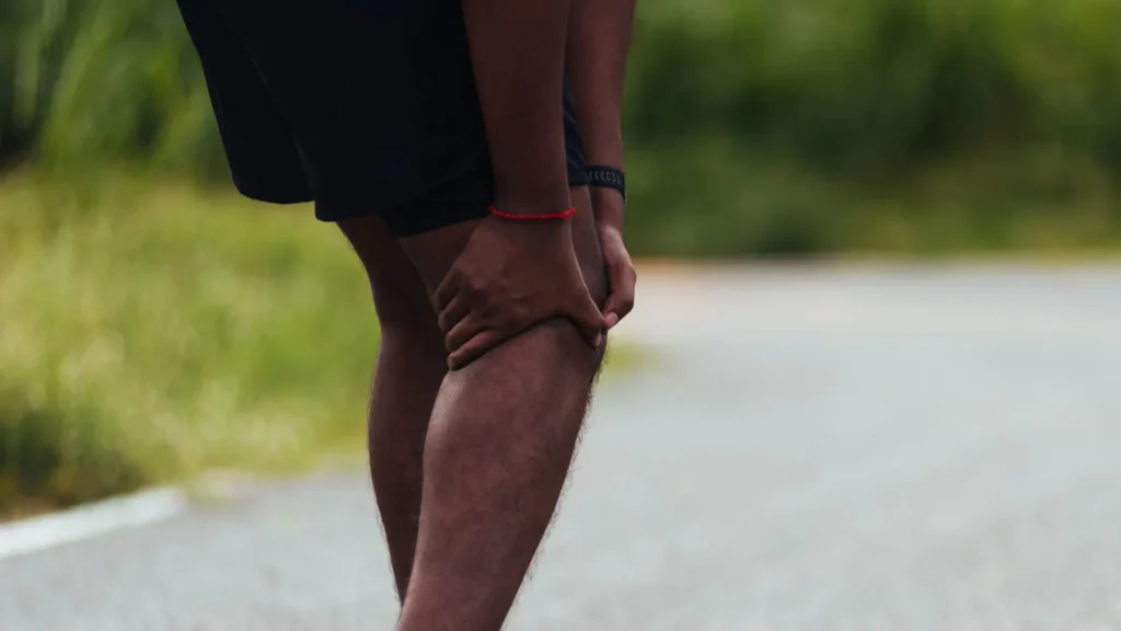 Crop shot of a Black man holding his knee in pain.