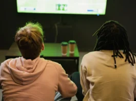 Back view of interracial friends watching sports match.
