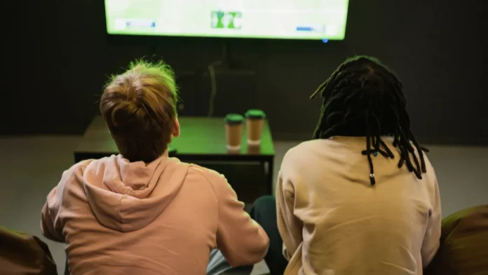 Back view of interracial friends watching sports match.