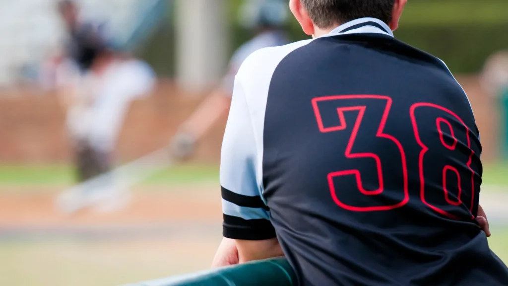 A baseball player watching the game from the dugout.