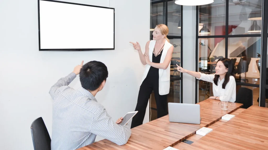 Business blonde woman and colleagues watching TV with blank scre