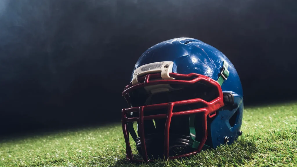 closeup shot of american football helmet on green grass with white smoke above