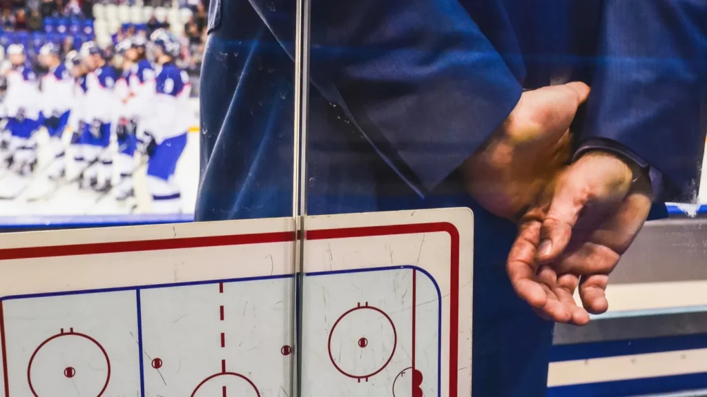 coach on the ice hockey bench with tactic board looking at player after hockey match