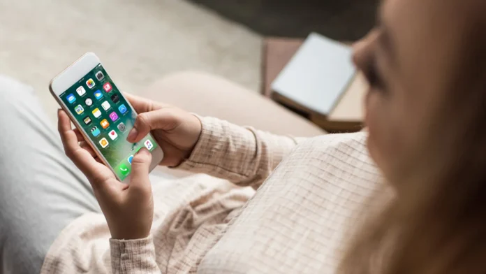 social media, cropped shot of woman on couch using smartphone with ios apps on screen cropped shot of woman on couch using a smartphone