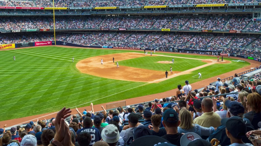 Aerial view of a sold-out Yankee Stadium with fans cheering during a baseball game.