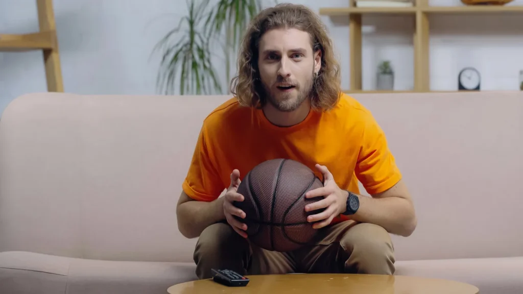 focused sport fan watching basketball match on tv at home