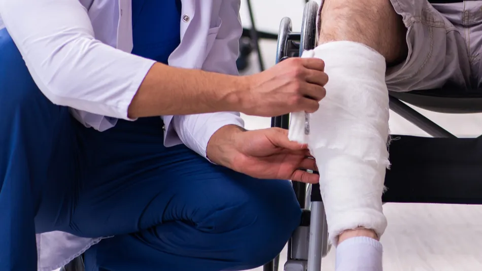 Old injured man visiting young male doctor traumatologist