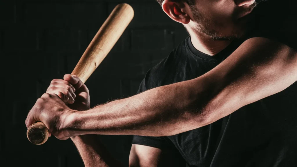 partial view of young sportsman playing baseball with bat isolated on black