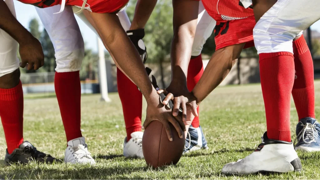 Photo of Football Players in Huddle Holding Football