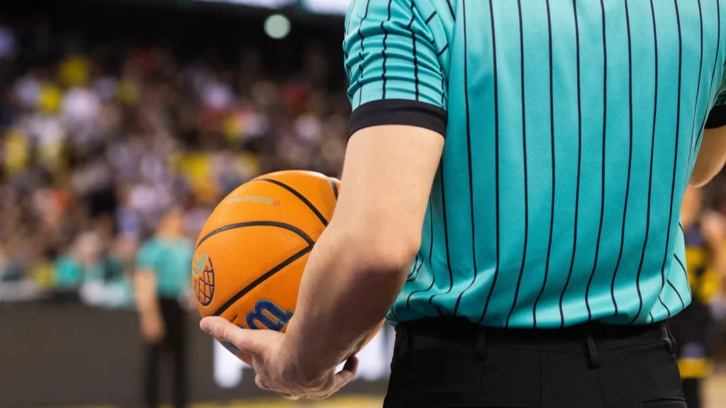 referee holding champions league basketball during game