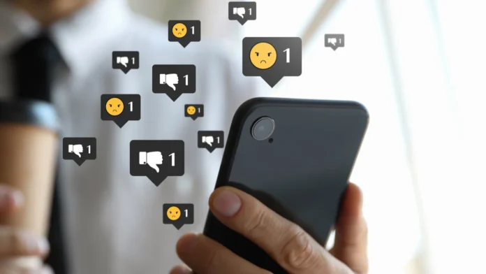 Social media dislike reaction Man using mobile phone indoors closeup Thumbs down and angry face emoji illustrations over gadget Social media dislike reaction